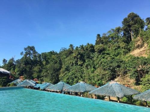a resort with blue water and straw umbrellas at La Casa Cita in Indang