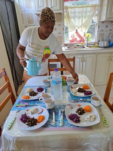 a woman standing at a table with plates of food at My local secret guesthouse in Salisbury