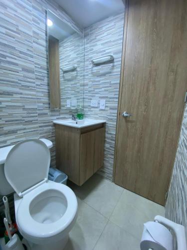a bathroom with a white toilet and a wooden door at Amoblado CTIC Calle 170 Norte Bogota in Bogotá