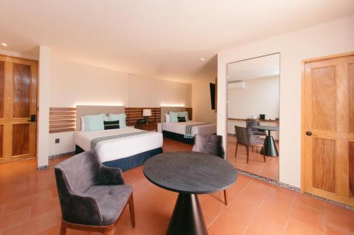a hotel room with two beds and a table and chairs at Casa Azulai Puebla Hotel Boutique in Puebla