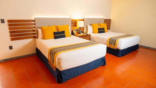 two beds in a hotel room with yellow pillows at Casa Azulai Puebla Hotel Boutique in Puebla