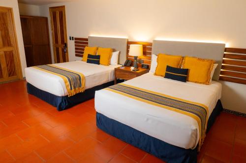 two beds in a hotel room with yellow and blue pillows at Casa Azulai Puebla Hotel Boutique in Puebla