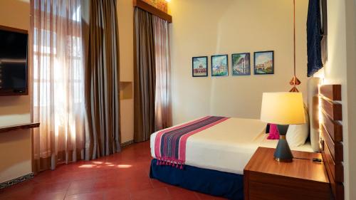 a bedroom with a bed with a lamp and a window at Casa Azulai Puebla Hotel Boutique in Puebla