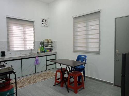 a kitchen with two windows and a table and chairs at Homestay KampungKU in Muar