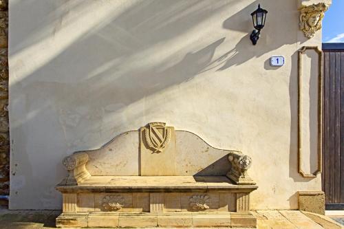 a stone bench sitting next to a white wall at Hotel Foresteria Baglio Della Luna in San Leone