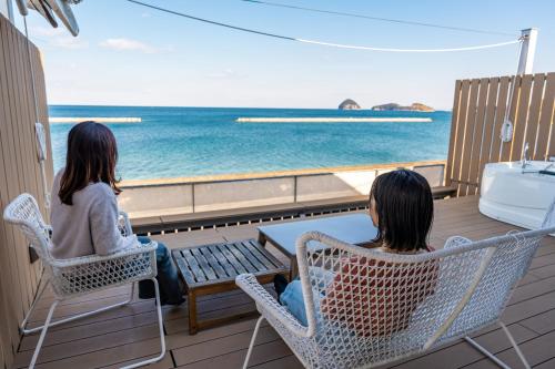 two women sitting in chairs on a balcony looking at the ocean at Beach SPA TSUDA 1 Uno in Sanuki