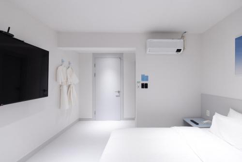 a white bedroom with a bed and a tv at Aank Ryokan x Aank Air Cheongju in Cheongju