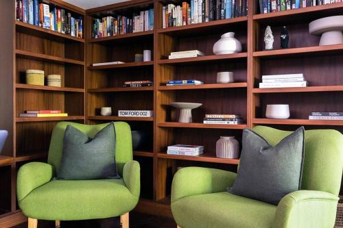 two green chairs in front of a book shelf at Villa Aman - Tropical Luxury with Infinity Pool in Port Douglas