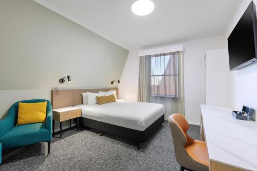 a hotel room with a bed and a chair at The Chancellor on Currie in Adelaide