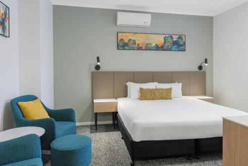 a hotel room with a bed and two chairs at The Chancellor on Currie in Adelaide