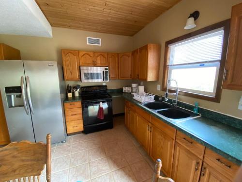eine Küche mit Holzschränken und einem Edelstahlkühlschrank in der Unterkunft Lake Michigan Beach House in Shelby