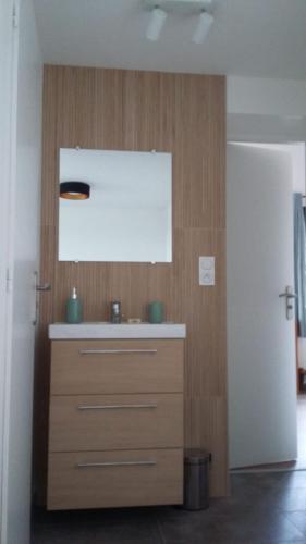 La salle de bains est pourvue d'un lavabo et d'un mur en bois. dans l'établissement un petit coin de paradis, à Anglet