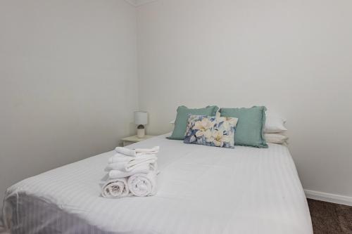 a bedroom with a white bed with towels on it at Newcastle CBD Penthouse, Spa & Entertainment in Wickham