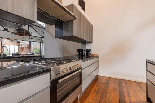 a kitchen with stainless steel appliances and wooden floors at Newcastle CBD Penthouse, Spa & Entertainment in Wickham