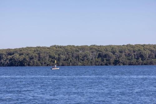 a small boat in the middle of a large body of water at Serendipity Stays Jervis Bay - 5 Mins Walk to Beach in Sanctuary Point