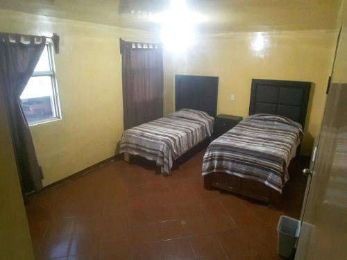 Dos camas en una habitación con ventana. en Casa Justo Sierra, en Durango