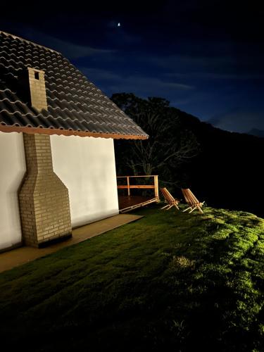a small white building with a roof on the grass at Cabana Reserve da Montanha - wi-fi in Camanducaia