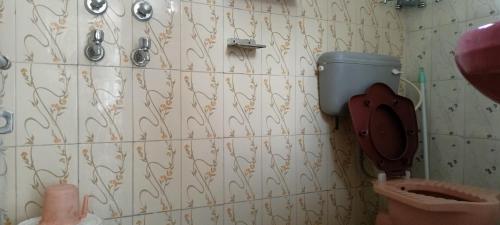 a bathroom with a toilet and a wall at Swami Samarpan Ashram in Rishīkesh