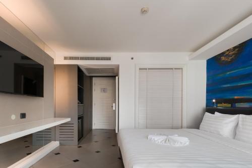 a bedroom with a white bed and a painting on the wall at Skye Hotel Bangkok in Bangkok