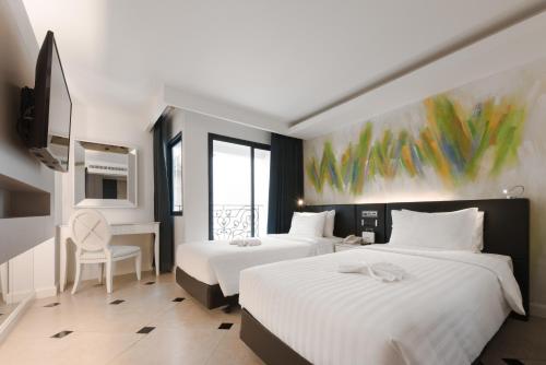 a hotel room with two beds and a table and chair at Skye Hotel Bangkok in Bangkok