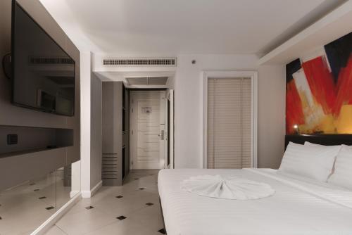 a bedroom with a white bed and a flat screen tv at Skye Hotel Bangkok in Bangkok
