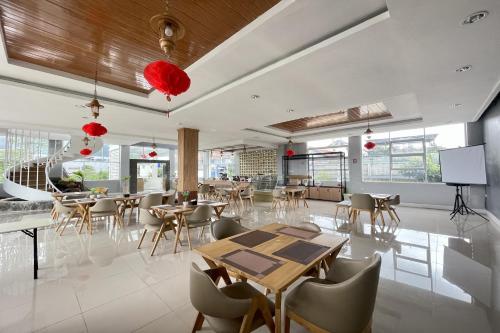 Un comedor con mesas y sillas y ventanas. en eLKa-eS Villa, en Cikareumbi 2