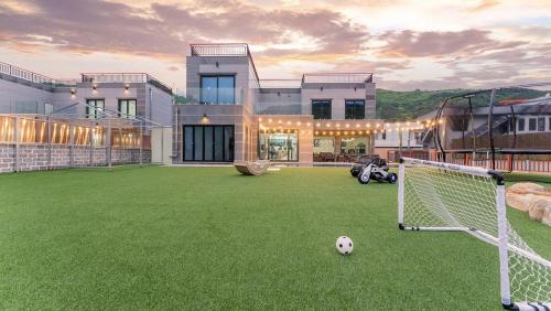 a soccer ball on a field in front of a house at Pause Kids Pool Viila A in Yeosu