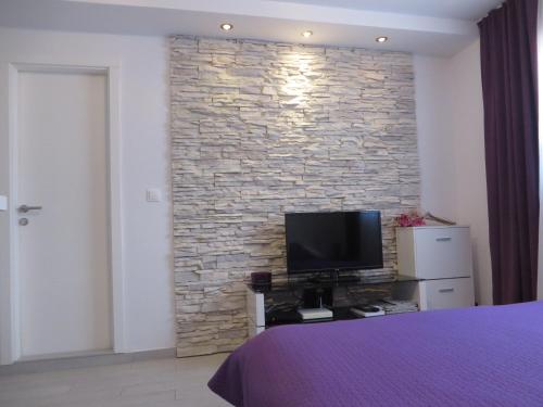 a bedroom with a stone wall with a television at Sea Gate Studio in Zadar