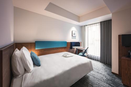 a hotel room with a large bed and a television at The Gate Hotel Yokohama by Hulic in Yokohama
