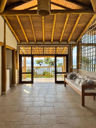 ein Wohnzimmer mit Couch und großem Fenster in der Unterkunft Suíte Deluxe com vista para Ilhabela in São Sebastião