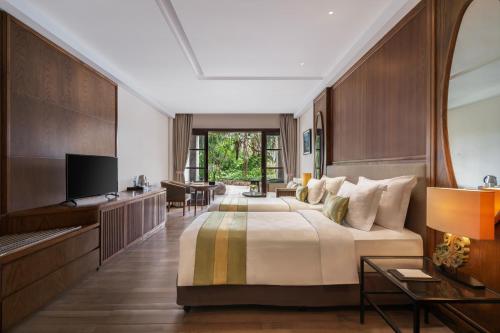 a hotel room with a bed and a television at Royal Tulip Springhill Resort Jimbaran in Jimbaran