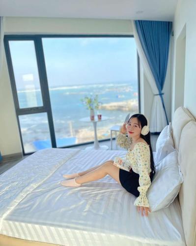 a woman sitting on a bed in a hotel room at Villa Làng Bè - Đảo Phú Quý in Cù Lao Thu
