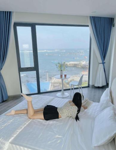 a woman laying on a bed in a room with a view at Villa Làng Bè - Đảo Phú Quý in Cù Lao Thu