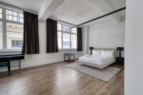 a white bedroom with a bed and a piano at High Street Luxury Loft in Auckland