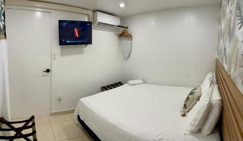 a bedroom with a white bed and a tv on the wall at Jazmin's Apartment in Oranjestad