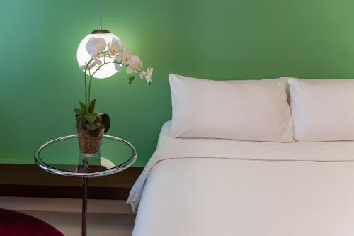 a bed with a glass table with a vase of flowers on it at The Picasso Boutique Serviced Residences Managed by HII in Manila