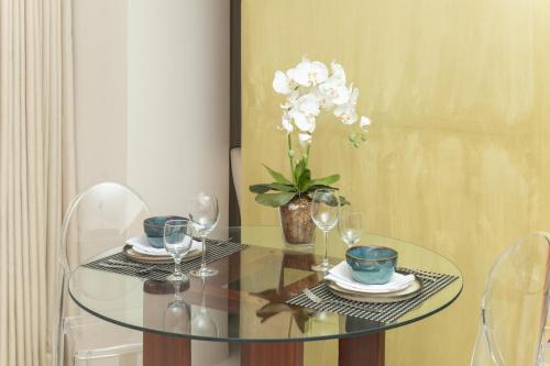 a glass table with two chairs and a vase with white flowers at The Picasso Boutique Serviced Residences Managed by HII in Manila