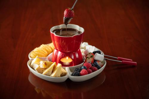 a cup of coffee and a bowl of fruit with a candle at Hilton Beijing Capital Airport in Shunyi