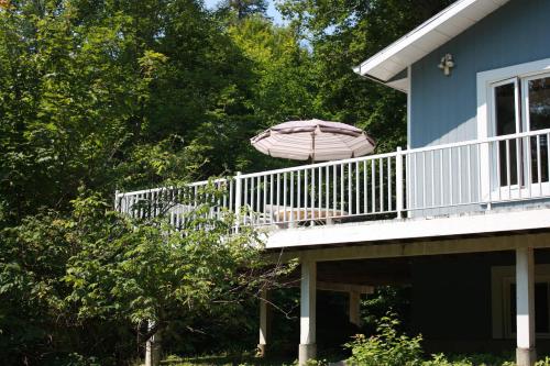 a deck with an umbrella and a table and chairs at Chalets et Studios Le Vent Du Nord in Lac-Superieur