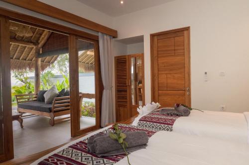 two beds in a room with a balcony at Ayunan Beach Villas Amed in Amed