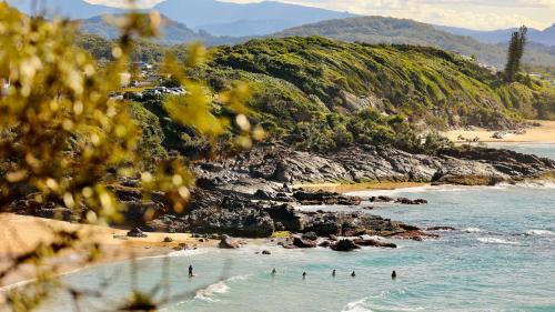 a group of people in the water on a beach at The Ranch Cabarita Beach - Tiny Home in Clothiers Creek