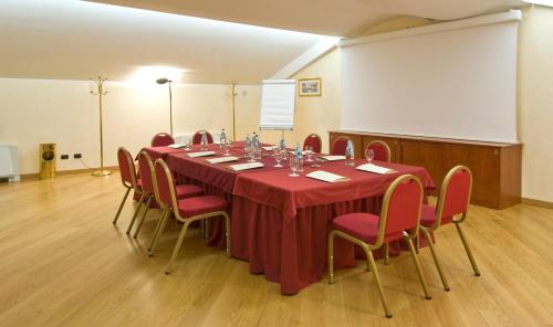 a conference room with a long table with red chairs at As Hotel Dei Giovi in Cesano Maderno