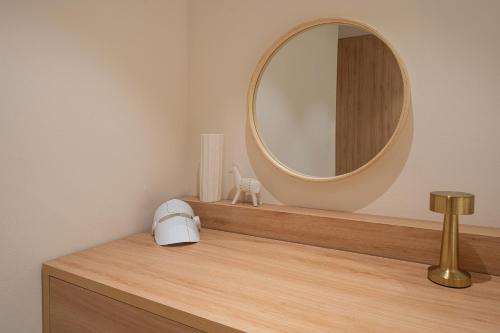 a mirror on top of a wooden dresser with a sink at The Mui Hotel in Seongnam