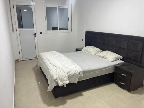 a bed with a black headboard in a bedroom at appartement neuf ideal in Monte ʼArrouit