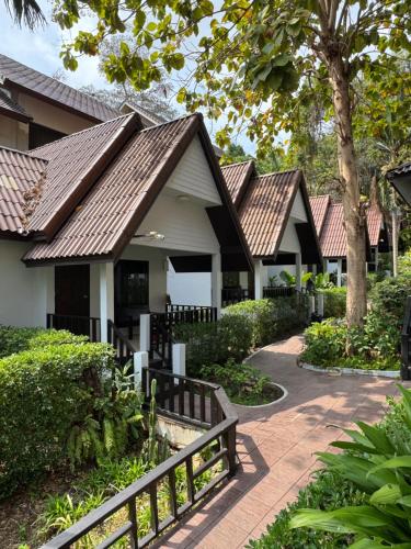 a row of houses with brown roofs and a walkway at Tok Little Hut in Rayong