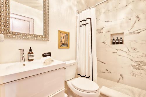 a white bathroom with a toilet and a shower at Beyond: Historic Rock & Roll Studio in Sunfair Heights