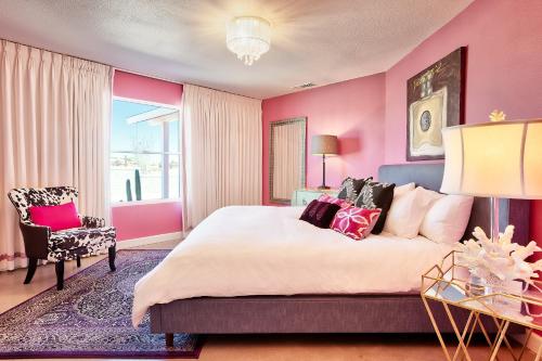 a pink bedroom with a large bed and a chair at Beyond: Historic Rock & Roll Studio in Sunfair Heights