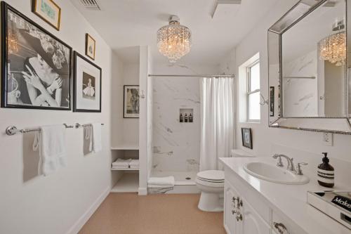 a white bathroom with a shower and a toilet and a sink at Beyond: Historic Rock & Roll Studio in Sunfair Heights