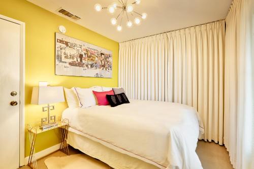a bedroom with a large white bed and yellow walls at Beyond: Historic Rock & Roll Studio in Sunfair Heights