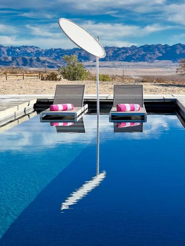 two chairs and an umbrella sitting on top of a pool at Beyond: Historic Rock & Roll Studio in Sunfair Heights